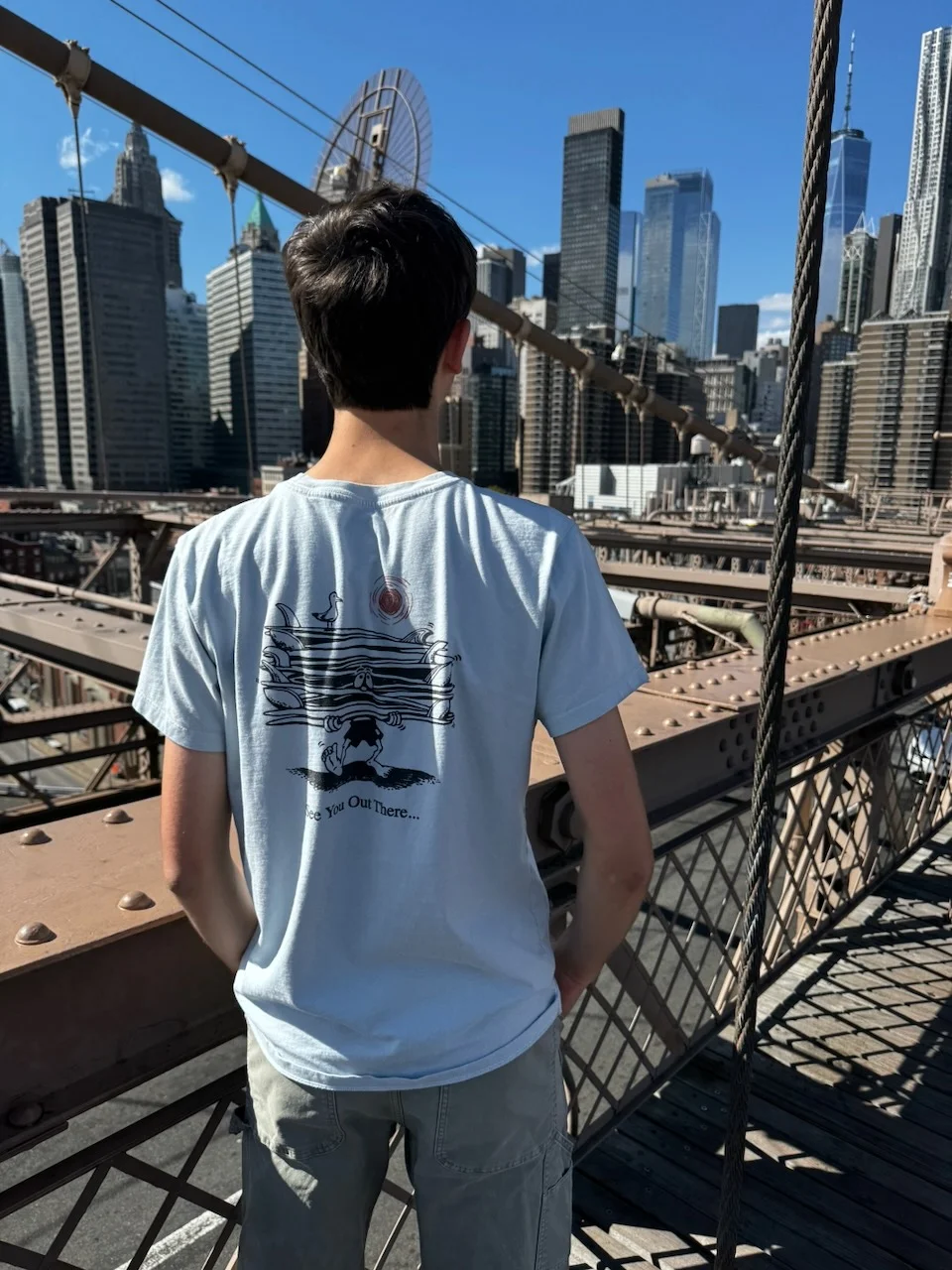 A person looking toward the Manhattan skyline from the Brooklyn Bridge
