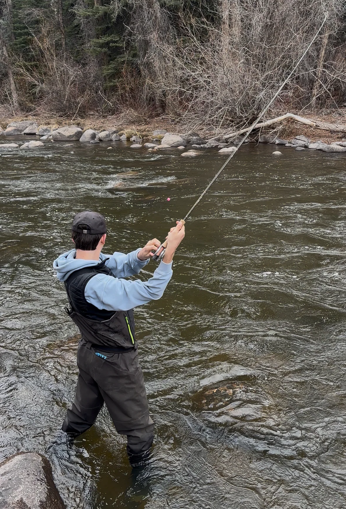Judah casting a fly line across a fast Colorado river