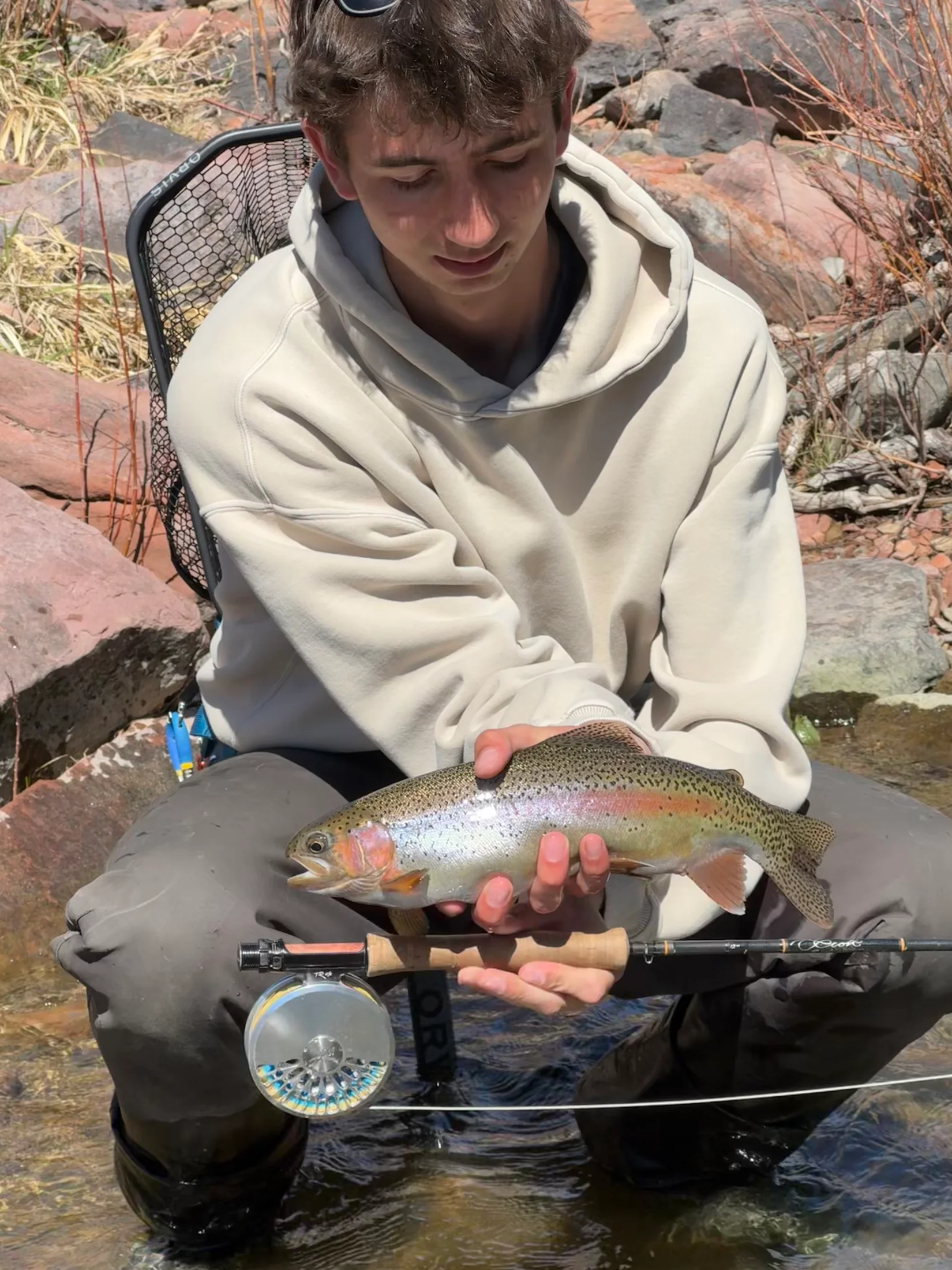 Judah cradling a rainbow trout at the edge of a Colorado creek