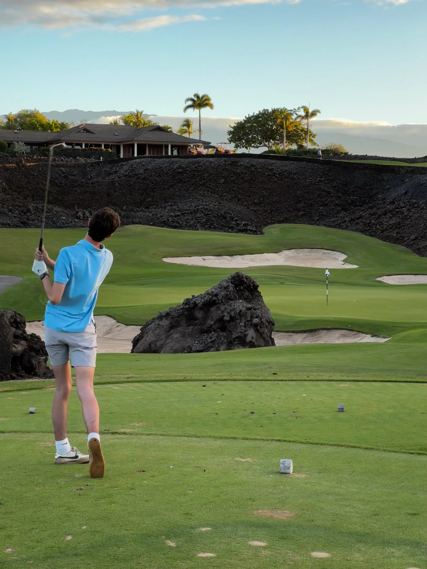Judah teeing off between lava rock and palms on the Big Island