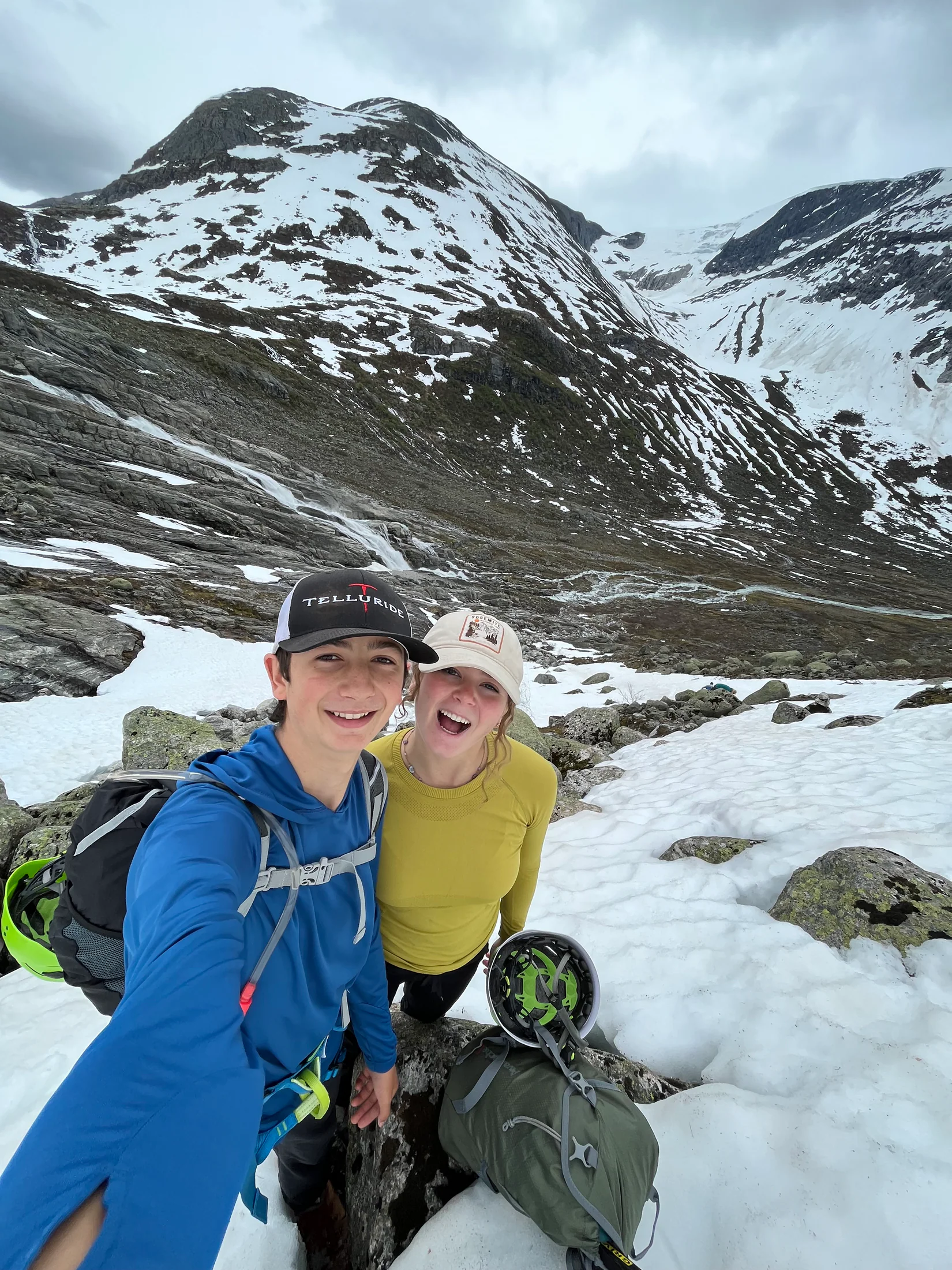 Two hikers smiling in a snow-filled mountain cirque above Fjærland