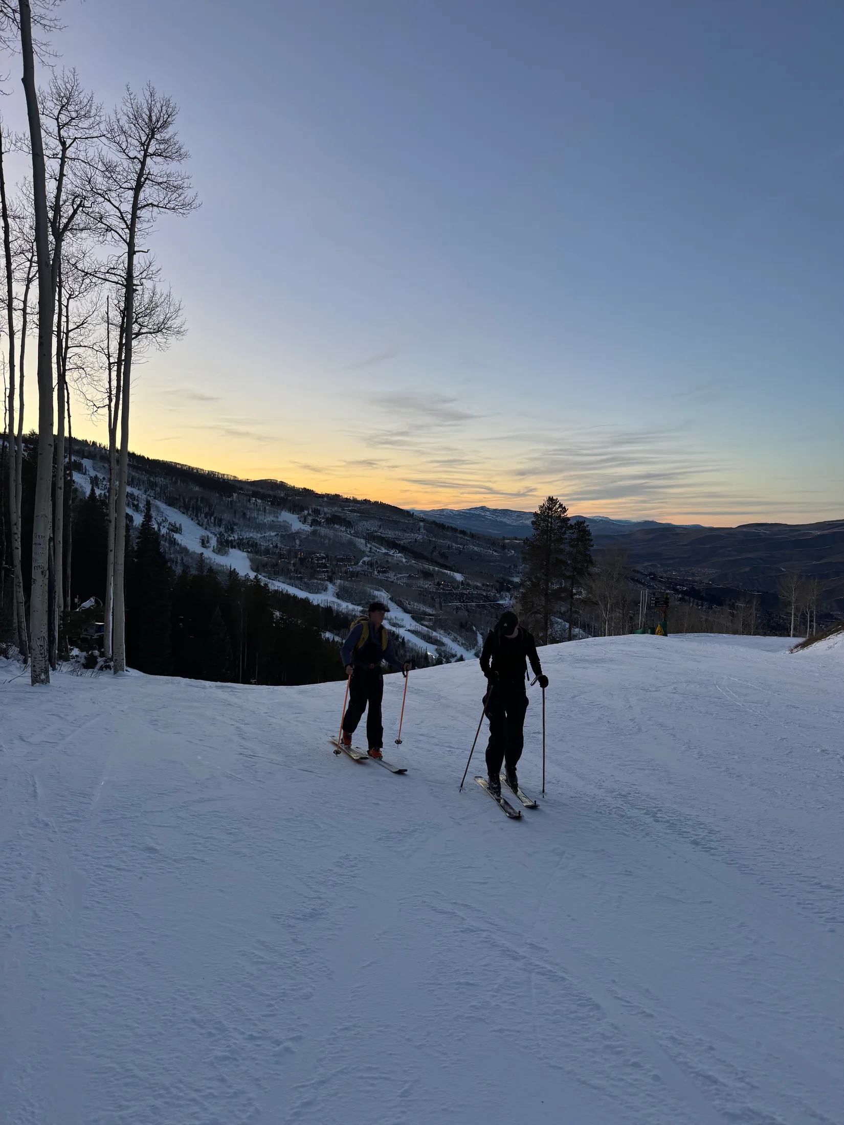 Two skiers traversing a mountain ridge at dusk